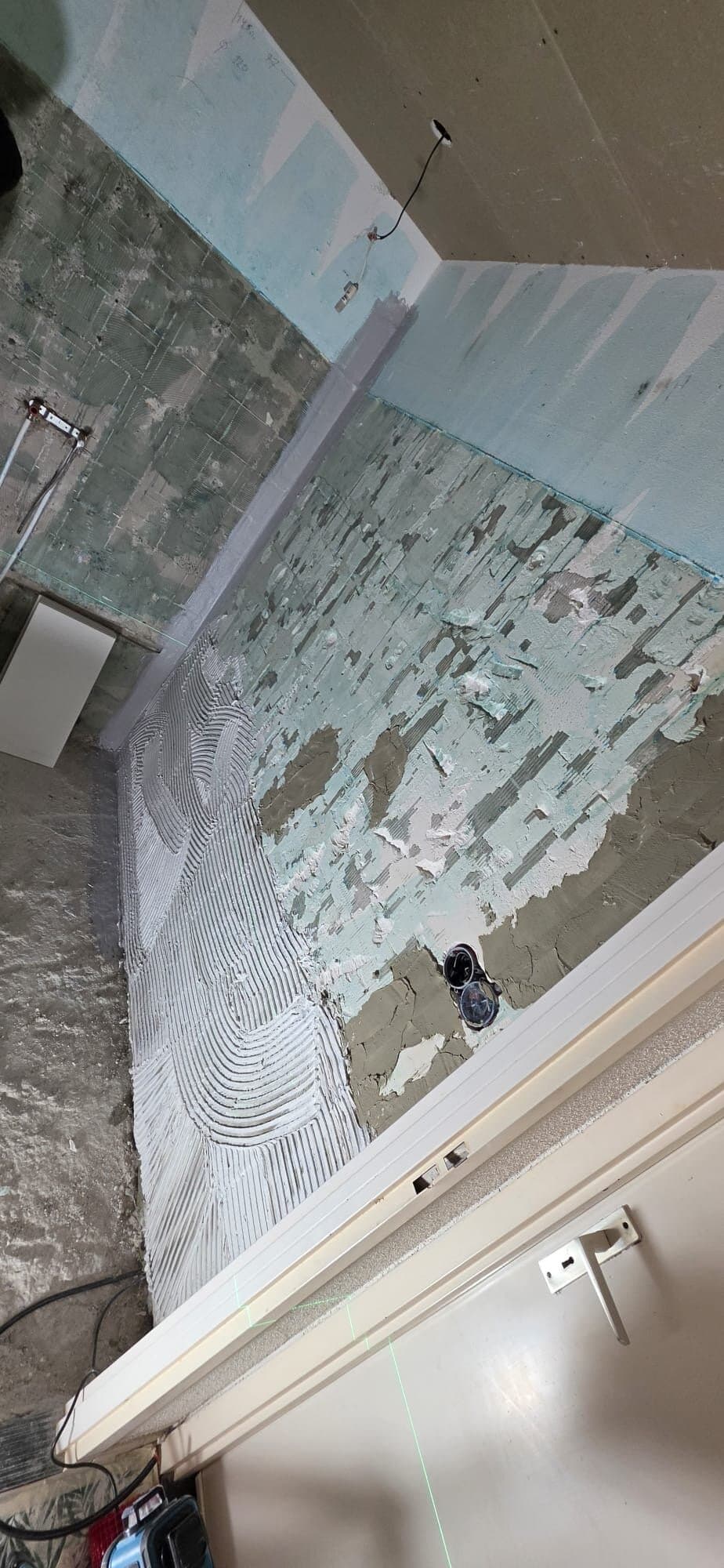 Badkamerwand met oude lijmresten, voorbereid op het nieuwe tegelwerk