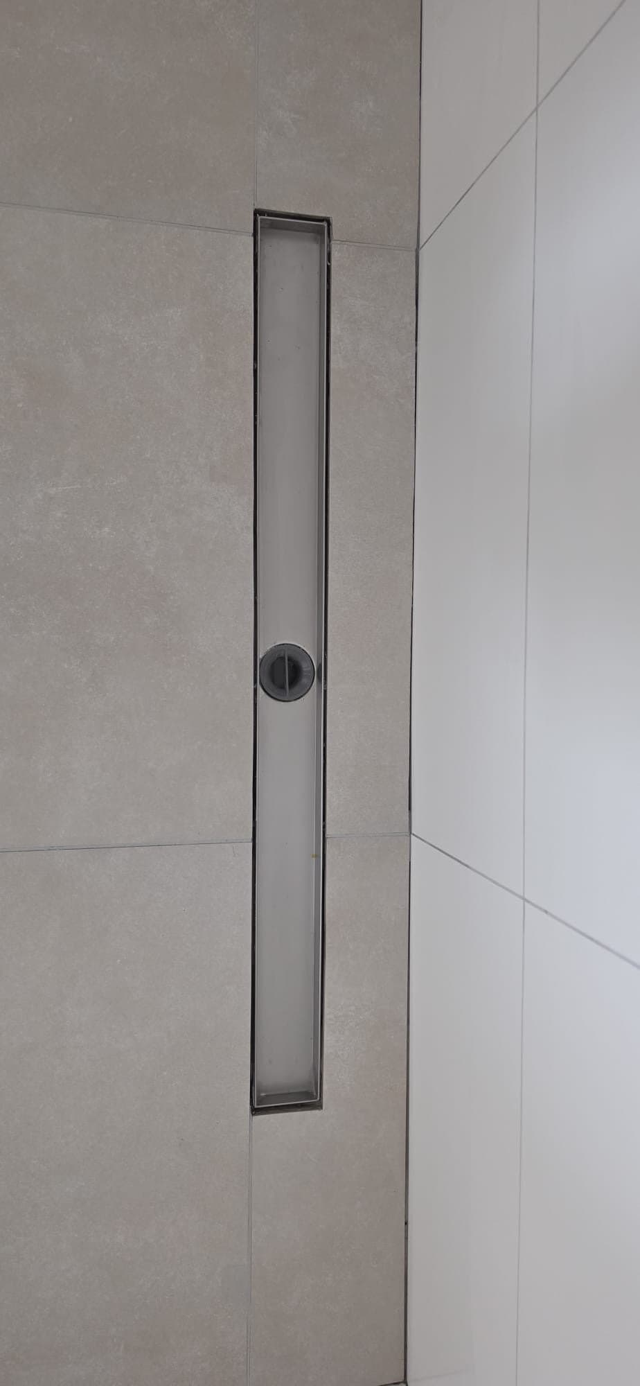 Lichte vloertegels met een vlakke douchegoot langs de wand