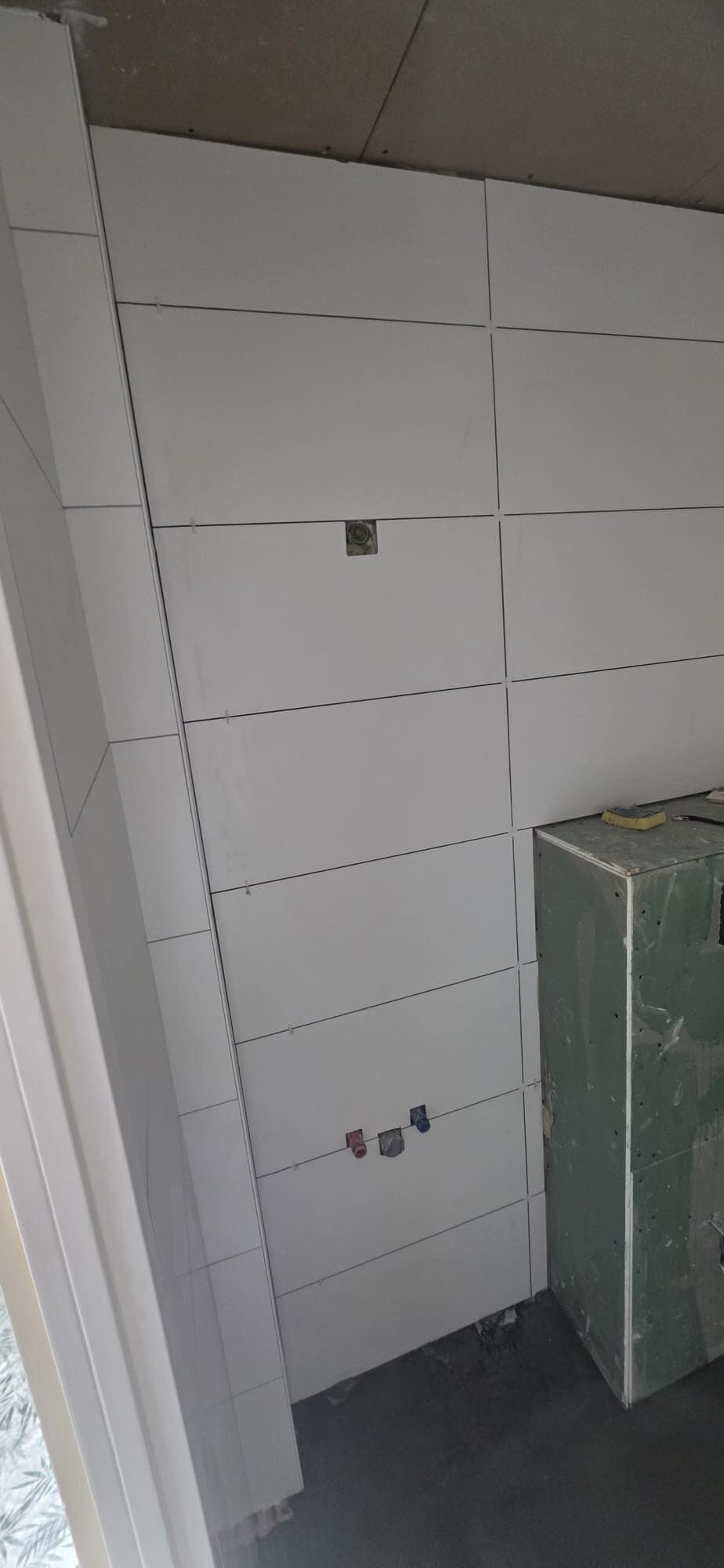 Witte wandtegels rondom de toiletaansluiting in een nieuwe badkamer