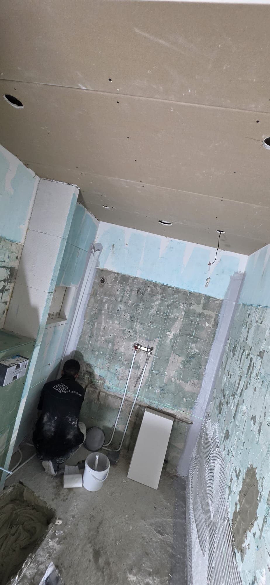 Tegelzetter aan het werk in een badkamer waar de oude tegels zijn verwijderd