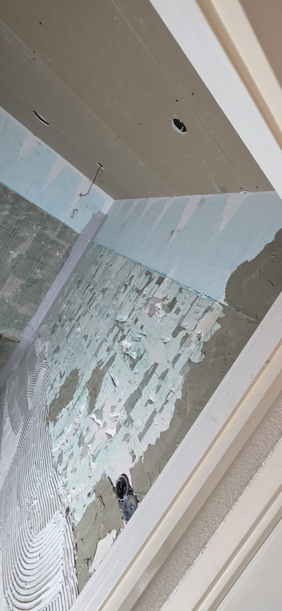 Gestripte badkamerwand met gekamde tegellijm, klaar voor nieuwe tegels